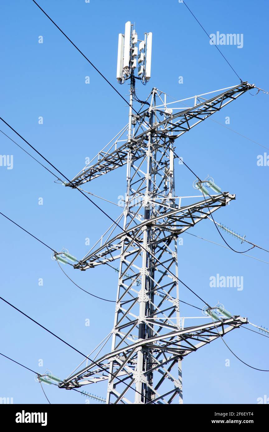 Polo elettrico per il trasporto di elettricità con antenna accesa in alto con un cielo blu chiaro Foto Stock