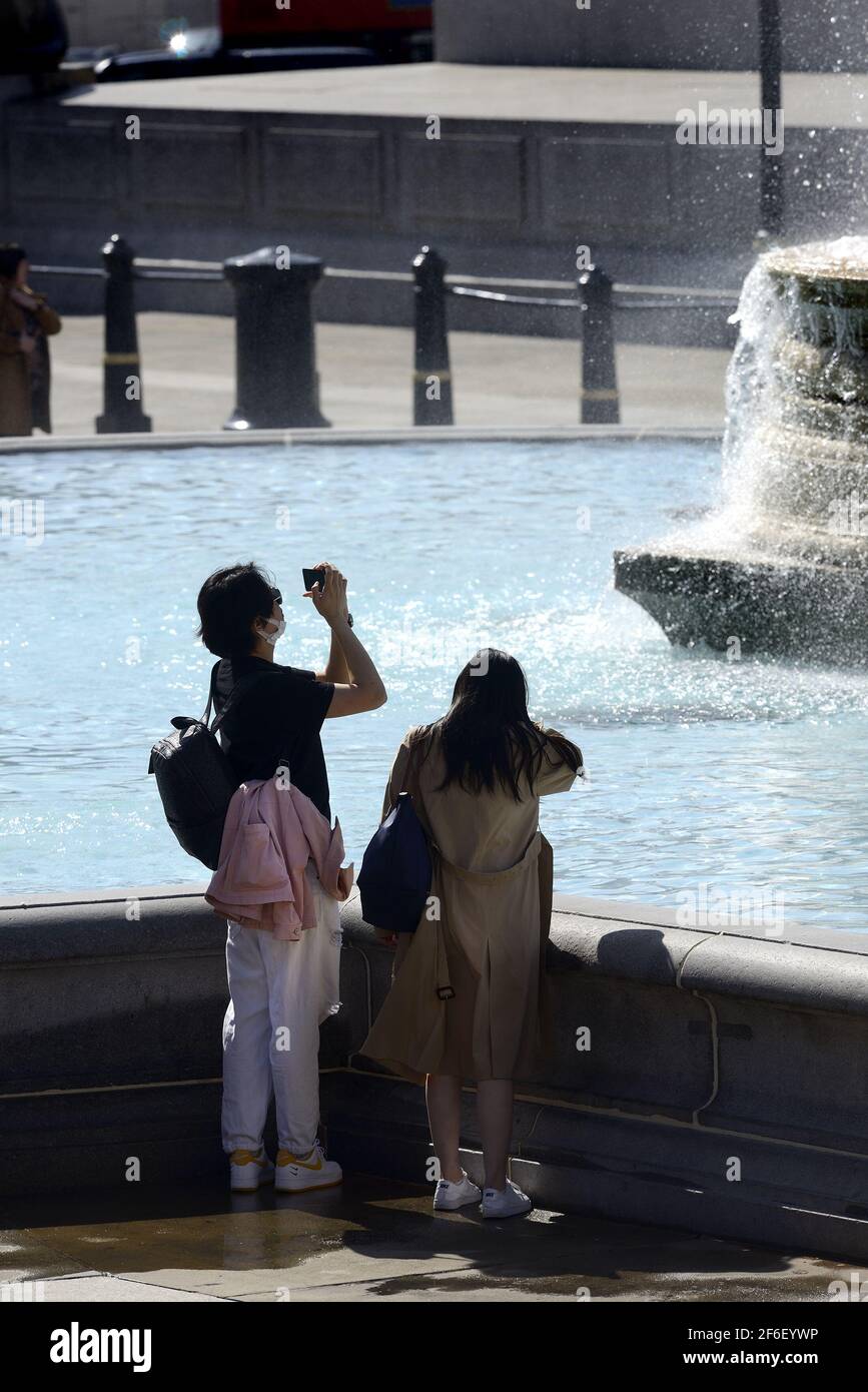 Londra, Inghilterra, Regno Unito. Trafalgar Square - giovane coppia asiatica che scatta foto durante la pandemia di COVID, marzo 2021 Foto Stock