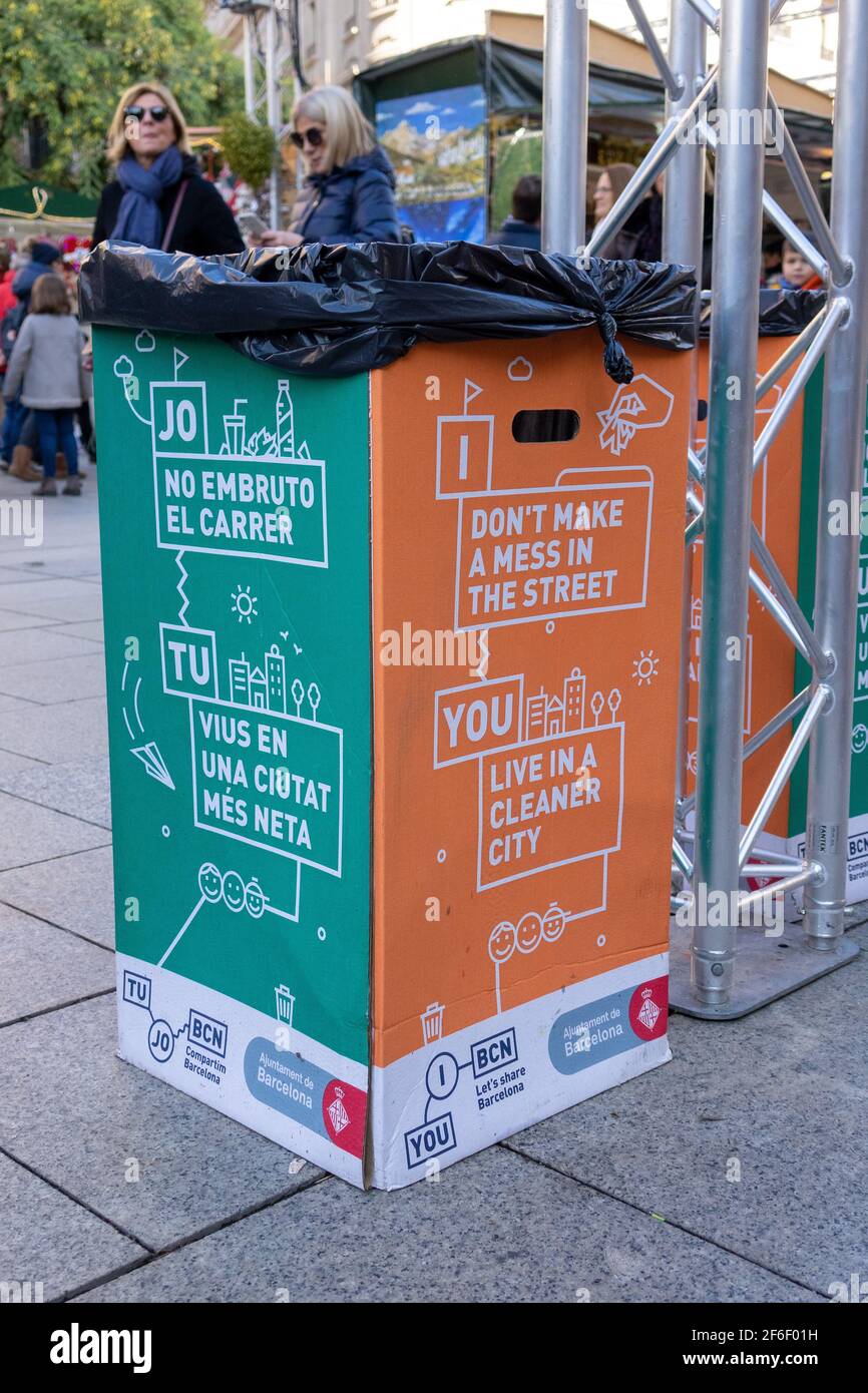 Cestino temporaneo di rifiuti di cartone a Barcellona Spagna con slogan Per mantenere una città pulita in inglese e spagnolo Foto Stock
