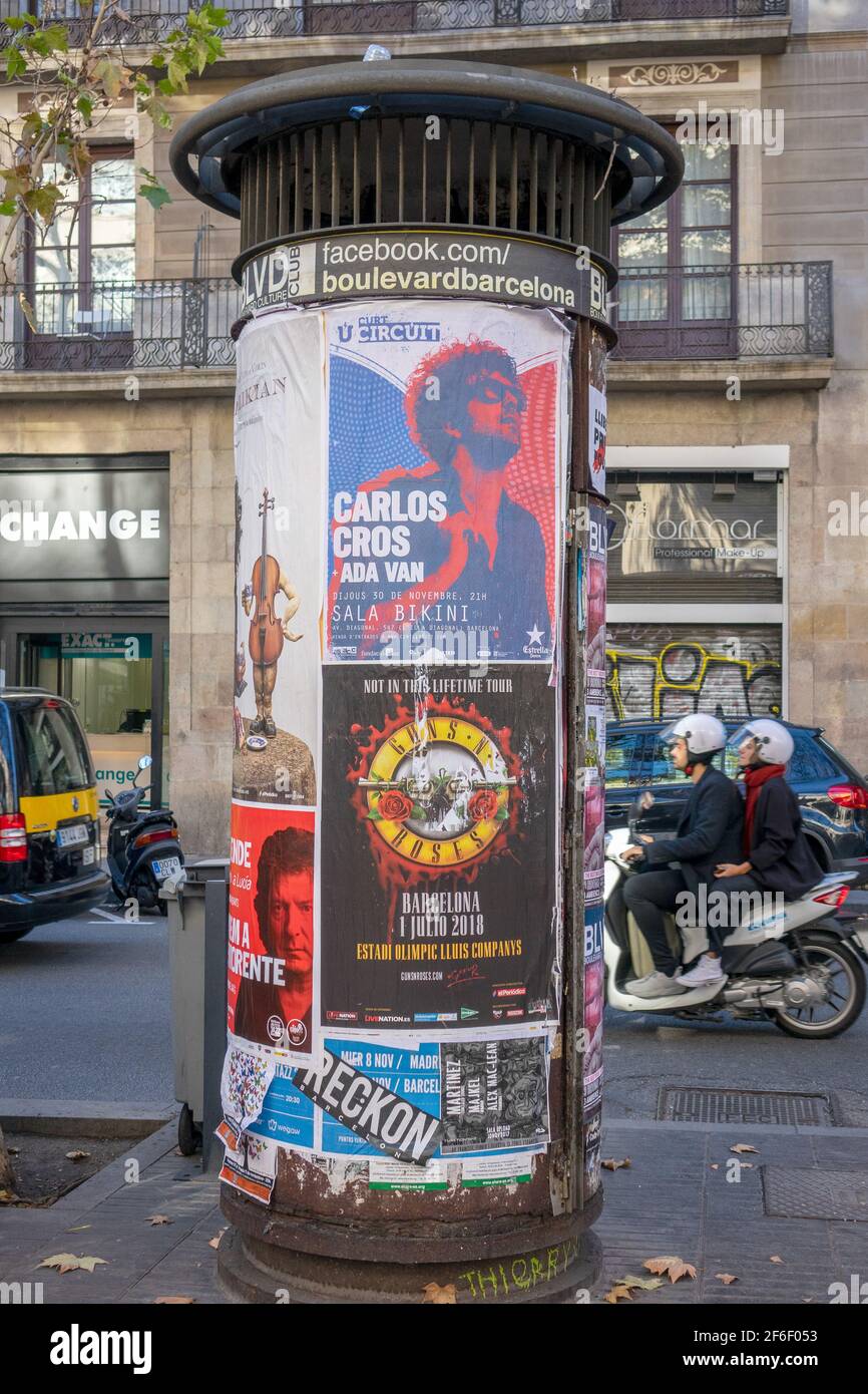 Una colonna Morris circolare circolare affissioni nel centro di Barcellona Spagna poster dei concerti di pistole e rose pubblicitarie Foto Stock