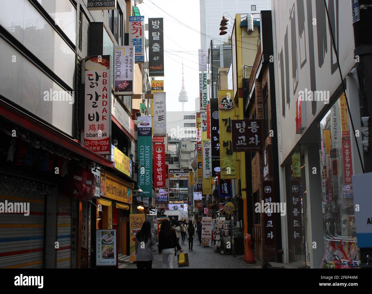 Vicolo commerciale nel centro di Myeongdong, Seoul, con vista a distanza della Torre di Namsan Foto Stock