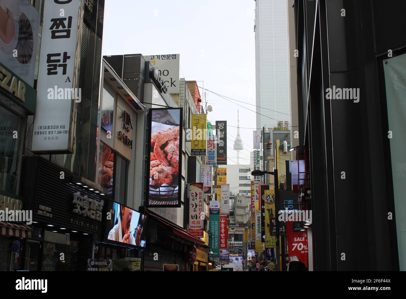 Vicolo commerciale nel centro di Myeongdong, Seoul, con vista a distanza della Torre di Namsan Foto Stock