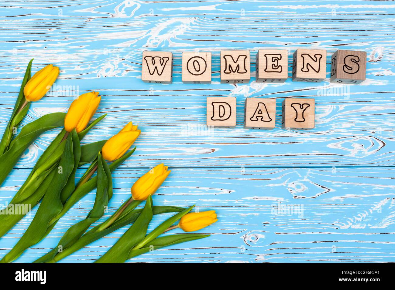Biglietto d'auguri con un giorno di donna l'8 marzo, tulipani gialli su sfondo blu Foto Stock