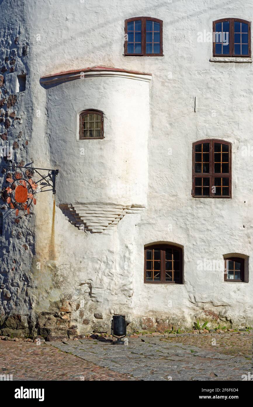 Facciata di un vecchio edificio con pareti bianche intonacate e finestre ad arco con bar nella parte vecchia della città di Vyborg. Foto Stock