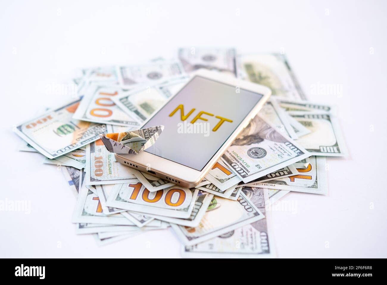 Token non fungibile NFT, cripto art, arte digitale, nuovo tipo di criptorurrenza. Telefono cellulare con testo NFT dorato in cornice dorata come oggetto d'arte su dollari Foto Stock