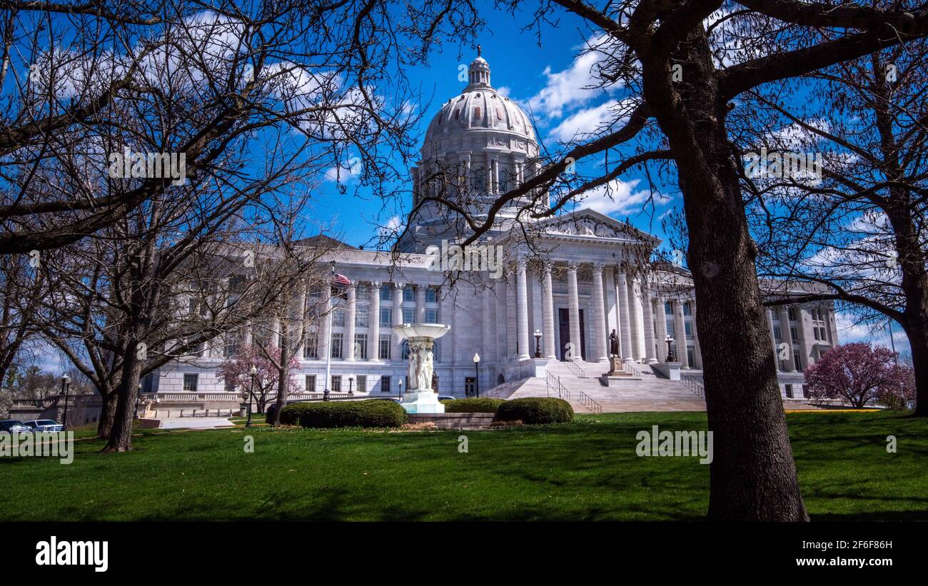 Vista dell'entrata frontale del campidoglio del Missouri con Cielo blu a Jefferson City in primavera con alberi con nessuna foglia in primo piano Foto Stock