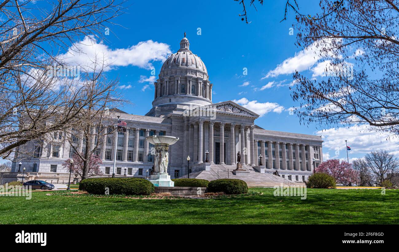 Edificio del campidoglio del missouri con cupola in marmo bianco e colonne Jefferson City con erba e alberi in primo piano con blu cielo primaverile Foto Stock