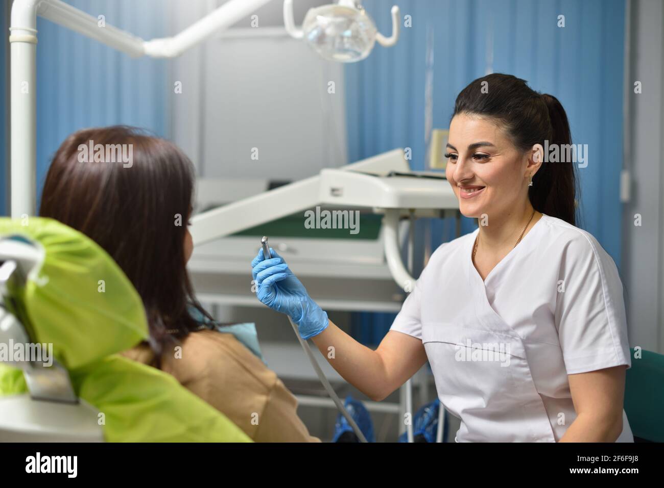 Donna dentista sorridente mentre lavora con paziente Foto Stock