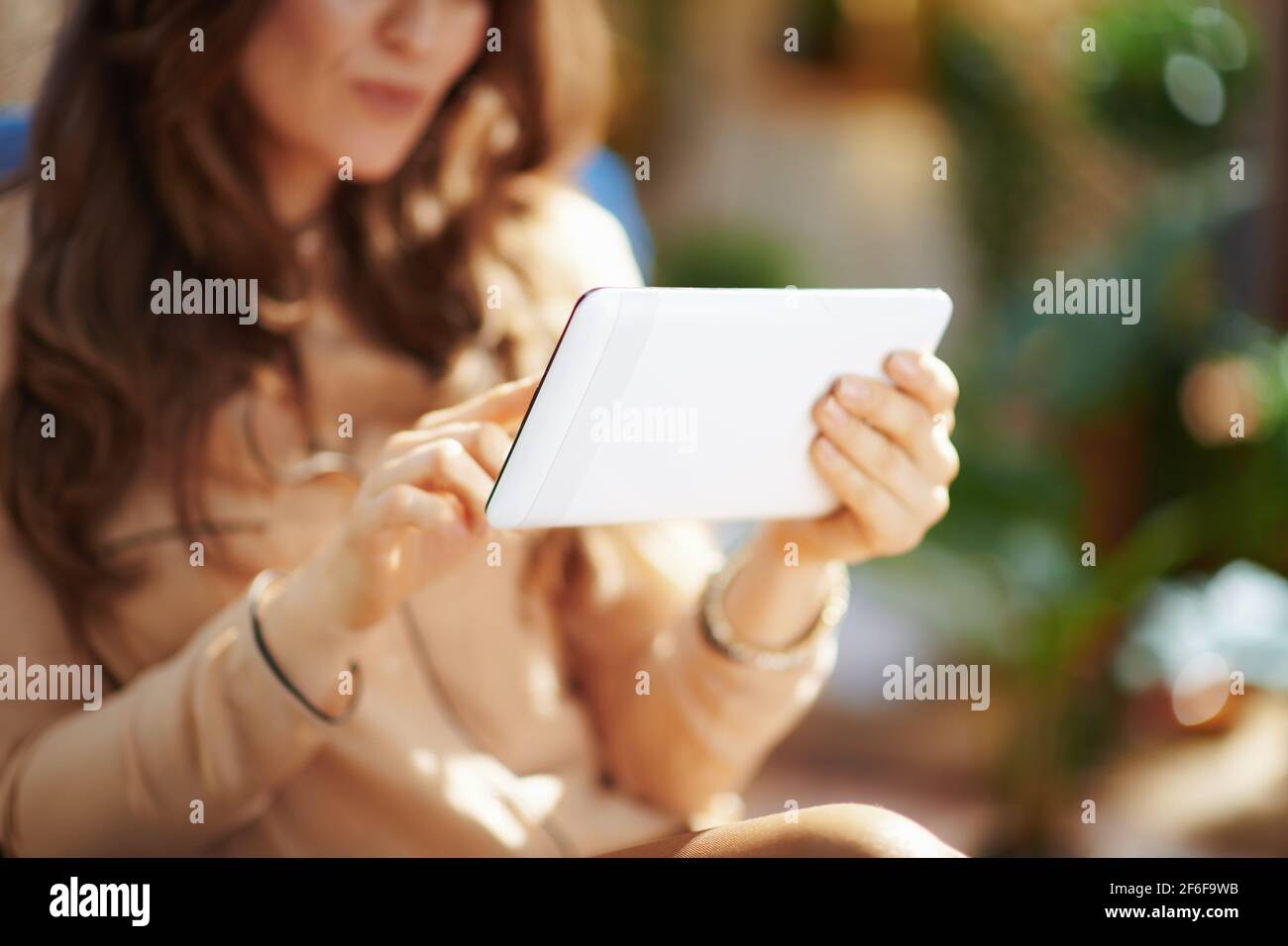 Home verde. Primo piano su una donna di mezza età in salotto in una giornata di sole utilizzando un tablet PC. Foto Stock