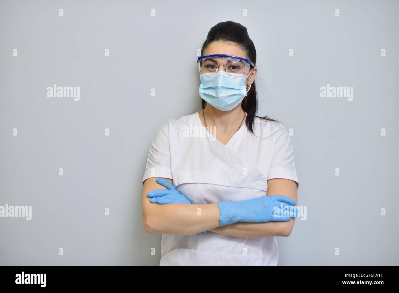 Cute donna dentista in uniforme, occhiali protettivi e maschera facciale Foto Stock