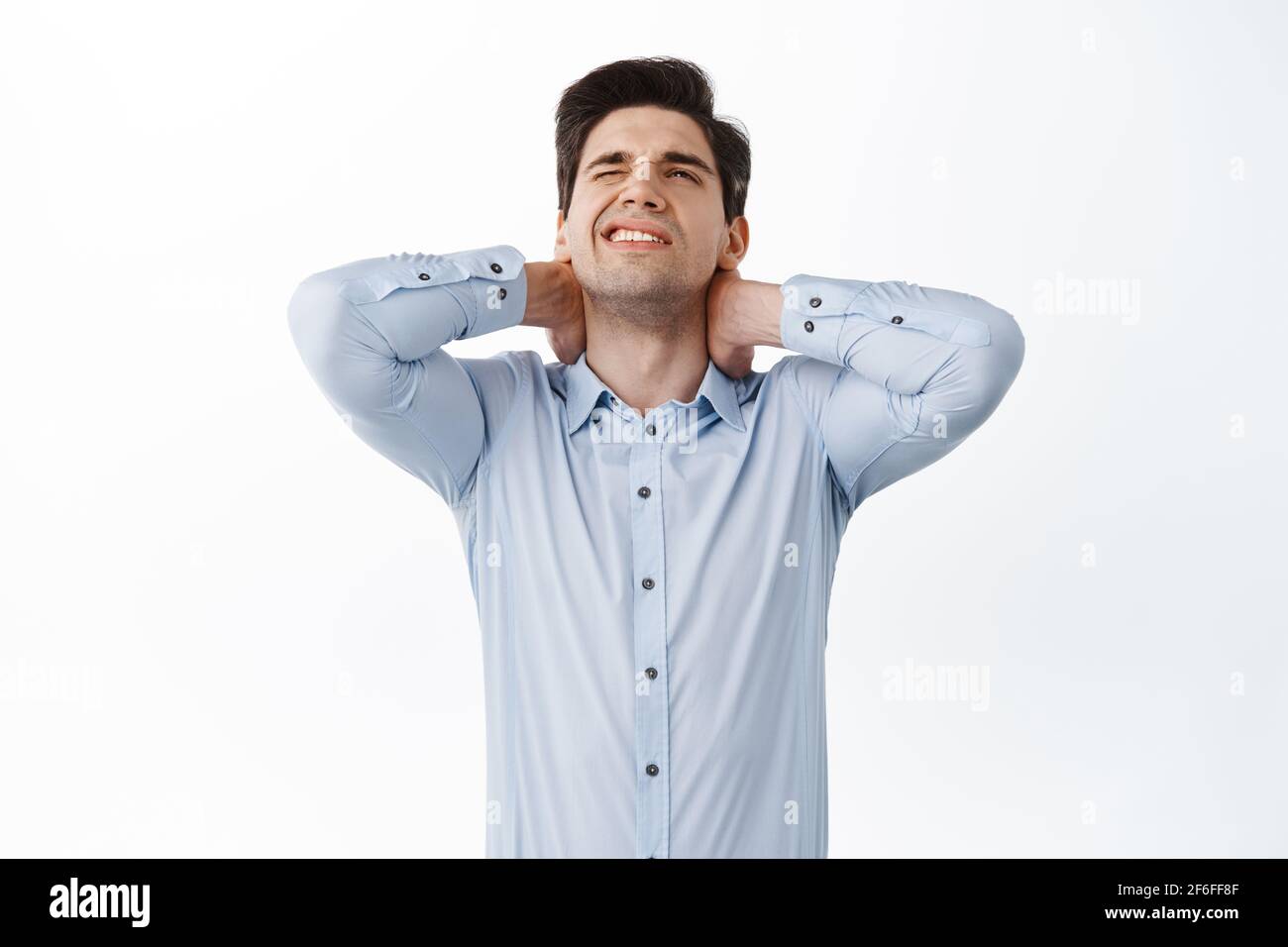 Lavoratore in ufficio, dipendente che ha mal di schiena, tocca mal di collo e grimacing da dolorosa sensazione dopo essere stato seduto al lavoro, hanno disagio, in piedi Foto Stock