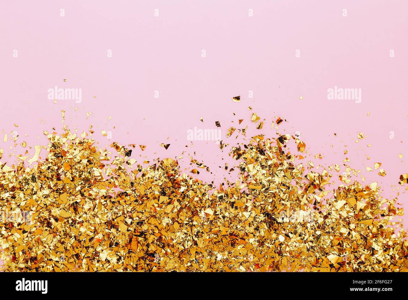 Confetti dorati su sfondo rosa. Sfondo delle vacanze, vista dall'alto Foto Stock