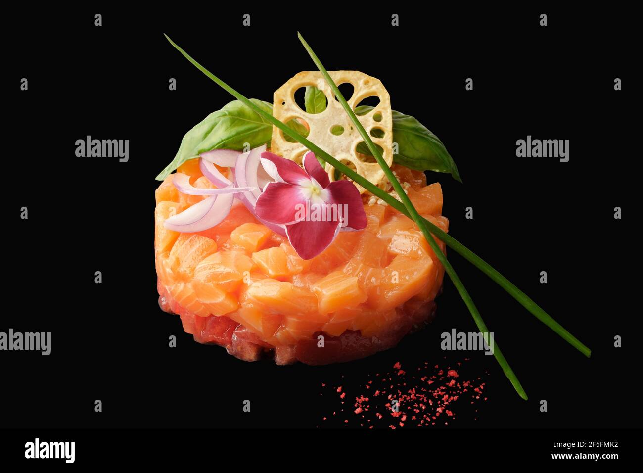 Tartare di salmone con pomodoro, cipolla rossa, aglio, basilico, capperi, radice di loto, caviale tobiko, limone, erba cipollina. Isolato su sfondo nero Foto Stock