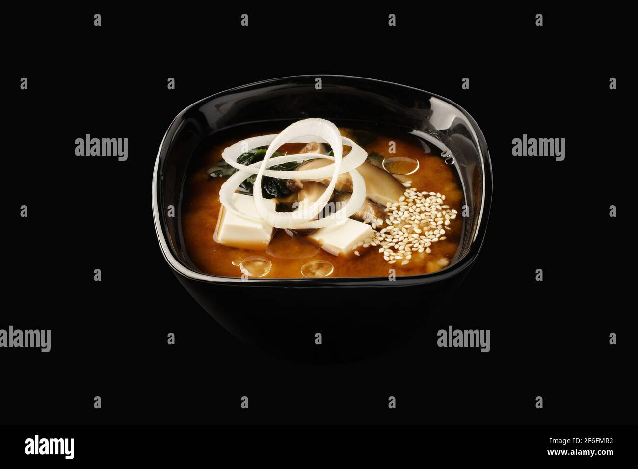 Zuppa di miso, funghi shiitake, formaggio tofu, alghe wakame, cipolle verdi, porri, semi di sesamo. Cibo giapponese. Isolato su sfondo nero Foto Stock