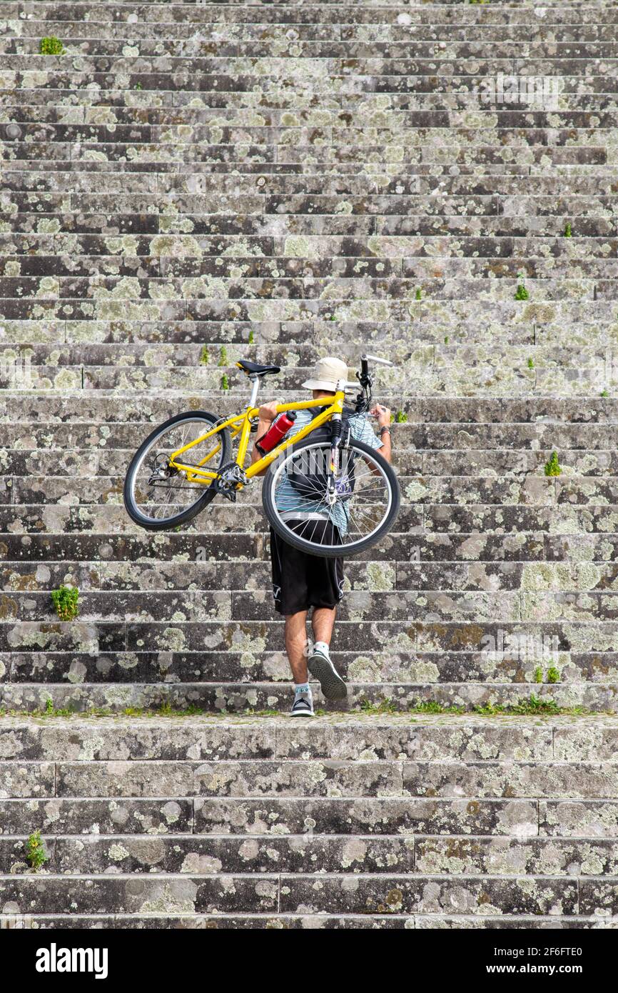 Giovane uomo che porta la bicicletta sulla schiena mentre sale le scale per un taglio corto nel Santuario di Sameiro a Braga, Portogallo. Foto Stock