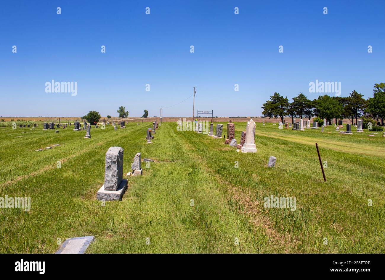 Paese americano cimitero fuori sulle pianure con alcune tombe Decorato per il Memorial Day e terreni agricoli in lontananza Foto Stock