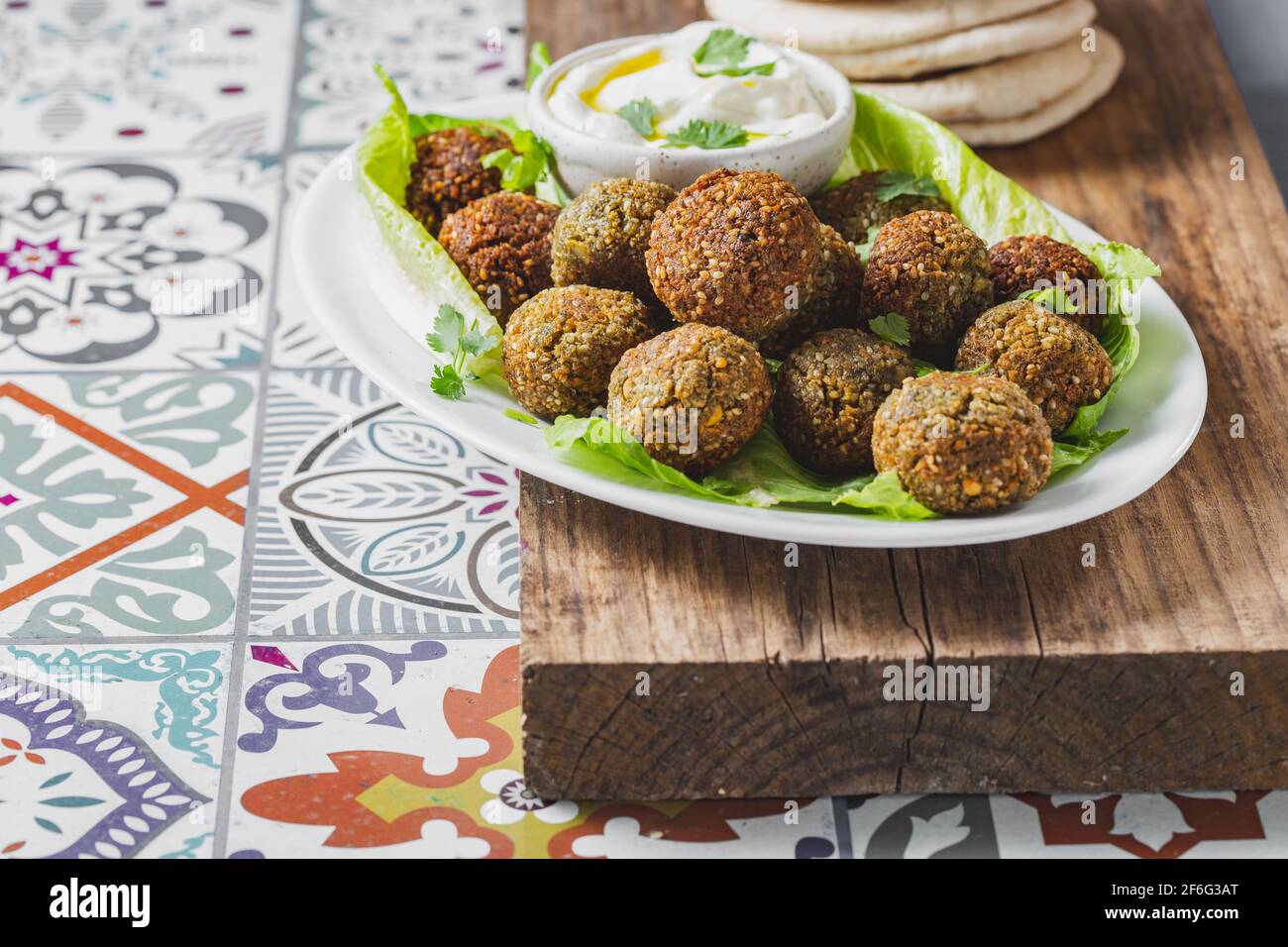 Polpette di falafel di ceci tradizionali fatte in casa con salsa bianca e pane pita su piatto bianco su tavola di legno, sano concetto di vita vegetariana. Israele Foto Stock