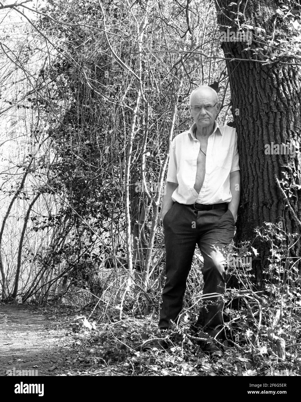 Marzo 2021 - uomo maturo in piedi da un albero dentro i boschi Foto Stock