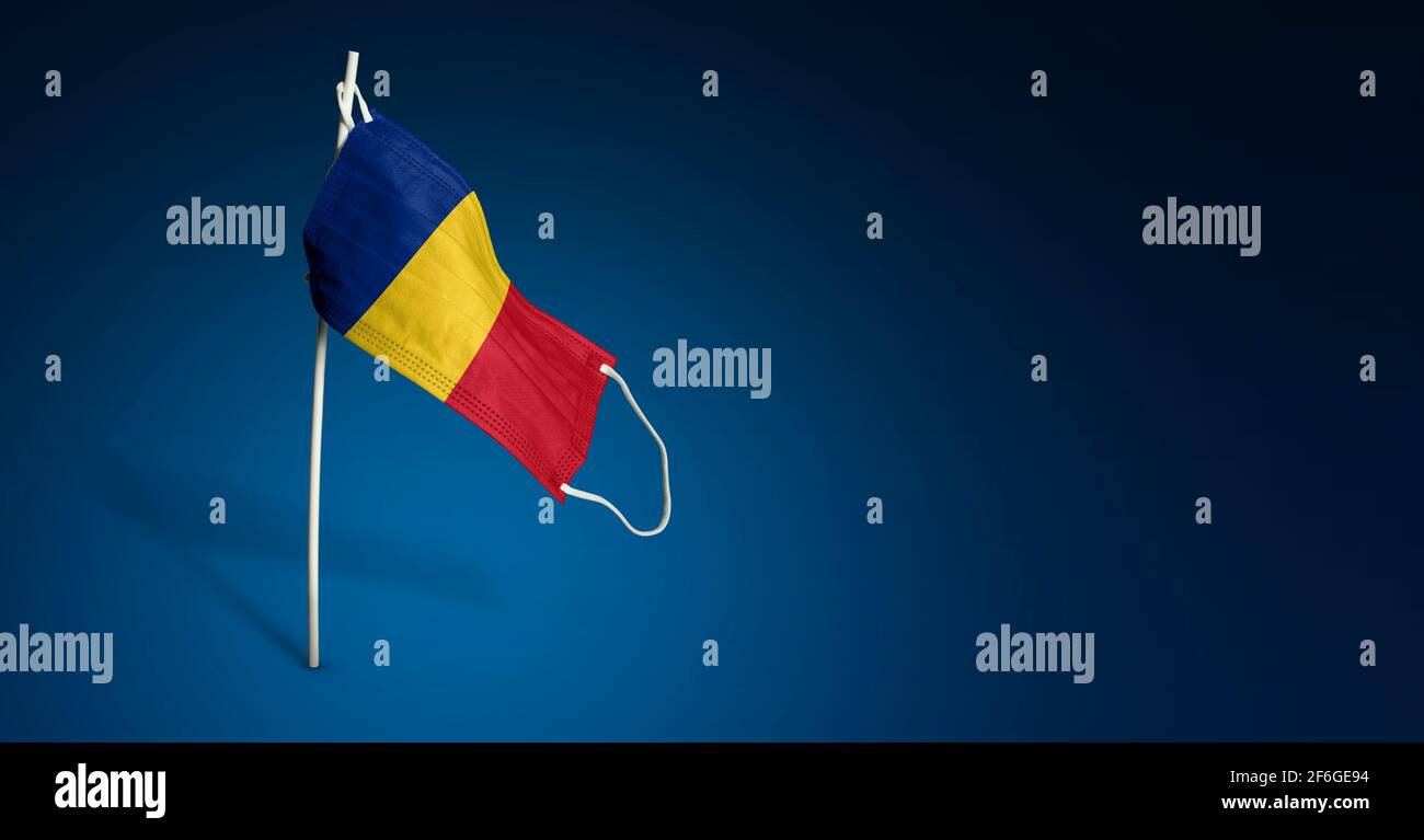Maschera Romania su sfondo blu scuro. Bandiera ondulata della Romania dipinta su maschera medica sul palo. Flag di attacco del virus. Concetto del banner della Fight ag Foto Stock
