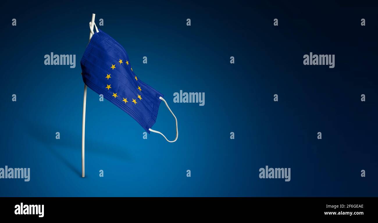 Maschera Unione europea su sfondo blu scuro. Bandiera ondulata dell'UE dipinta su maschera medica sul palo. Flag di attacco del virus. Concetto della bandiera della lotta Foto Stock