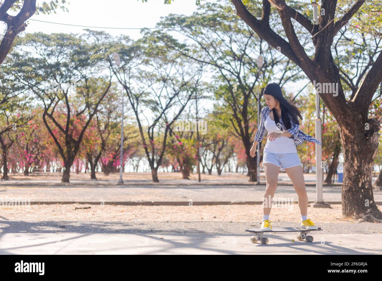 Le giovani donne asiatiche giocano a surf skate board al Park skate ramp all'aperto la mattina. Le donne felici giocano a bordo di surfskate al parco. Attività sportive stile di vita co Foto Stock