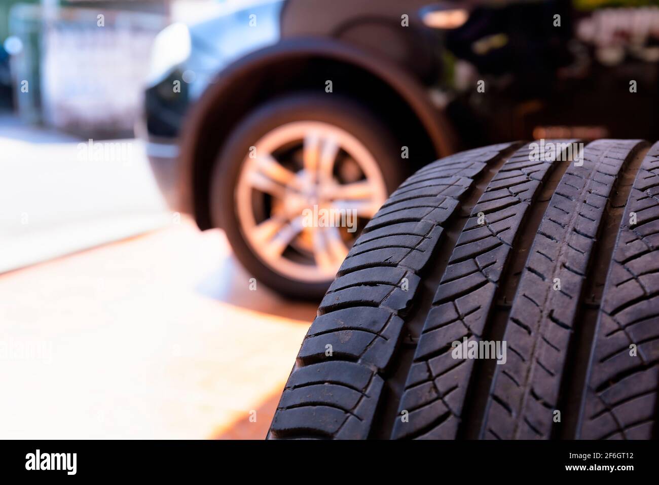 Primo piano del vecchio pneumatico con lo sfondo della ruota dell'auto. Officina pneumatici e sostituire la vecchia ruota sulla vettura. Pneumatici per auto usate impilati in pile al servizio di montaggio pneumatici Foto Stock