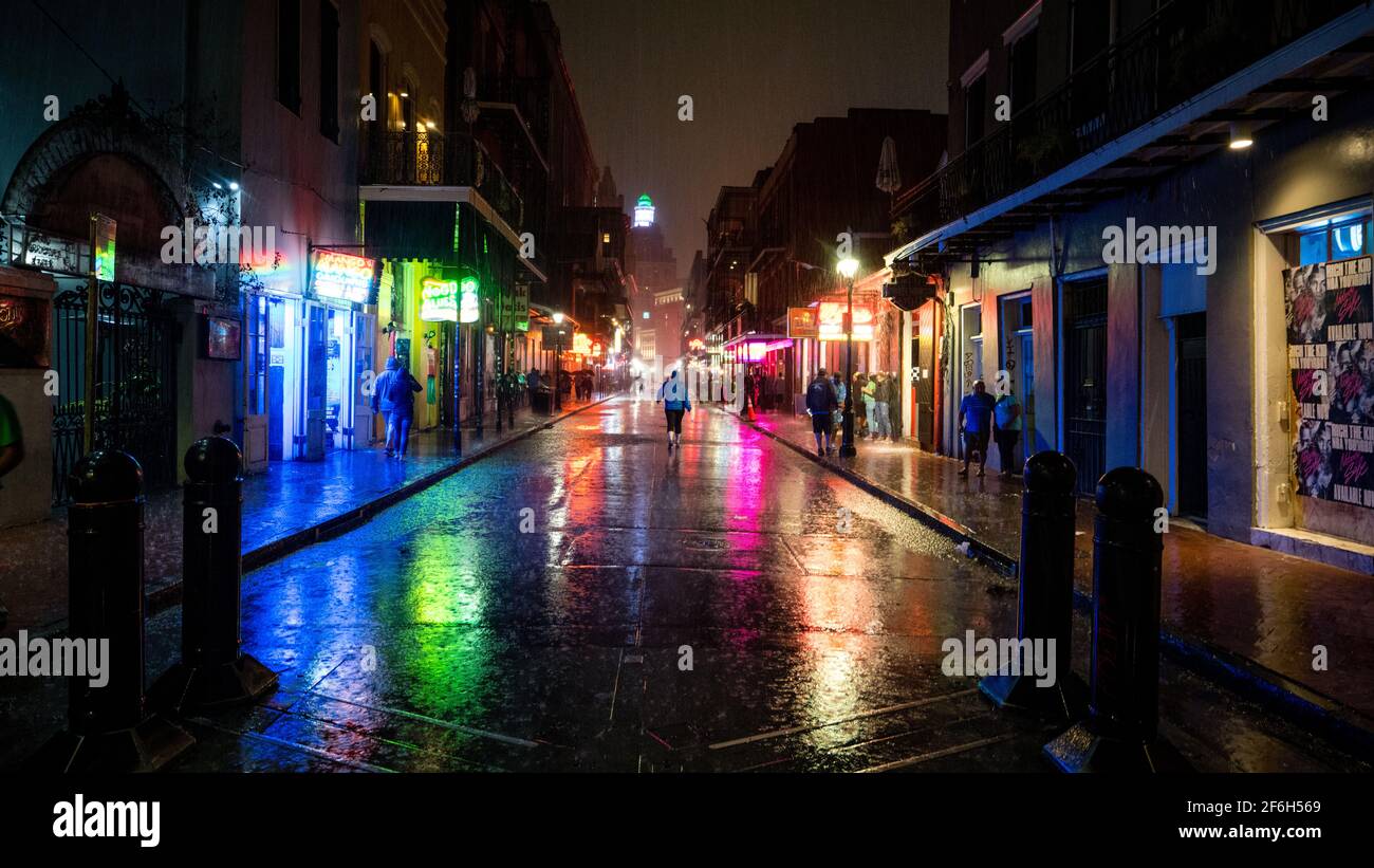 Un singolo visitatore cammina lungo Bourbon Street a New Orleans, Louisiana, in una notte piovosa nel marzo del 2021 dopo una grande tempesta. Foto Stock