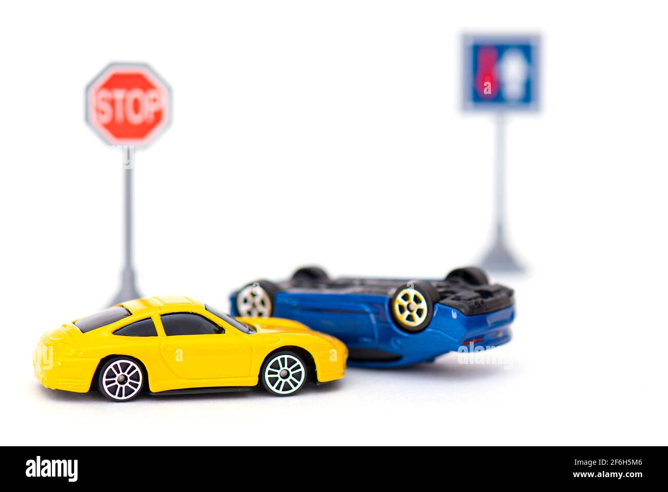 Incidente con due auto giocattolo e segno stop isolato su bianco. Immagine concettuale sull'incidente stradale Foto Stock