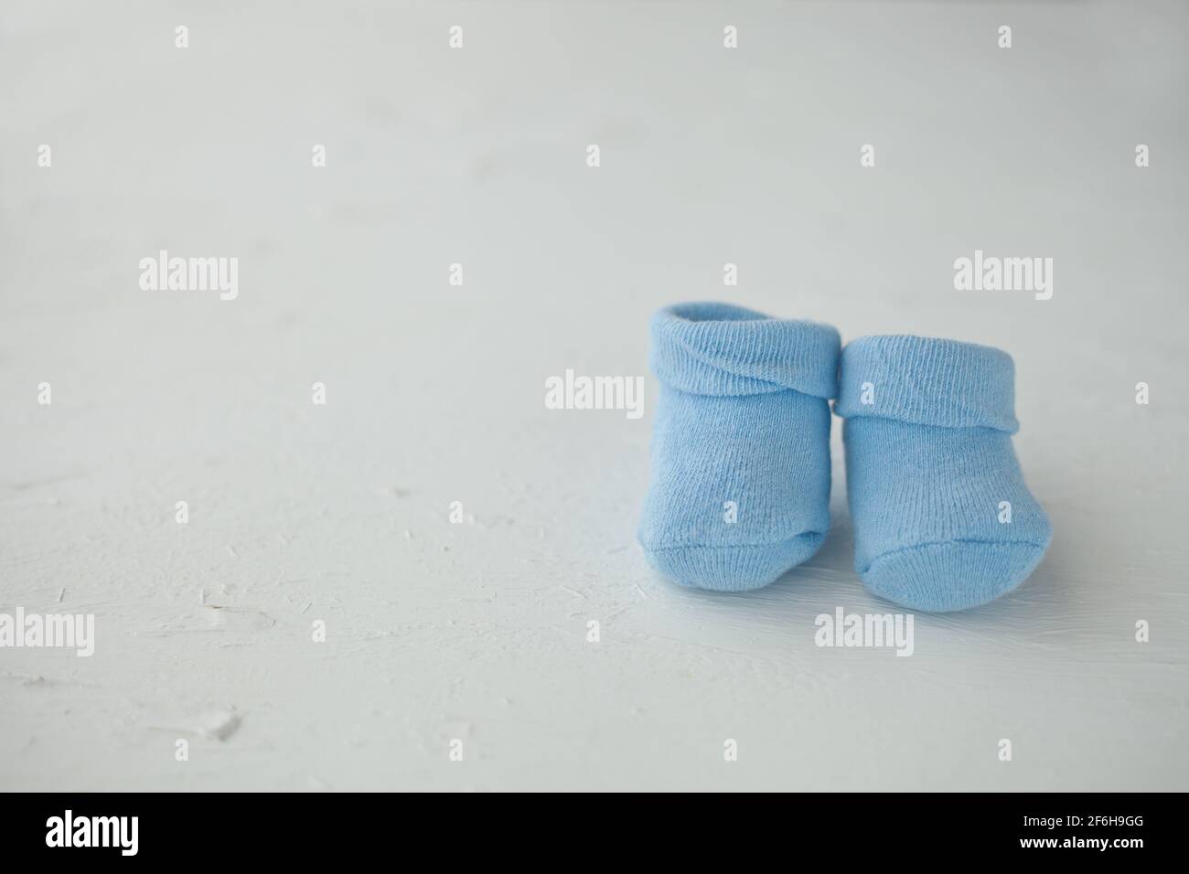 Calze blu per bambini su sfondo rustico testurizzato con spazio per la copia. Concetto di neonato e gravidanza. Foto Stock