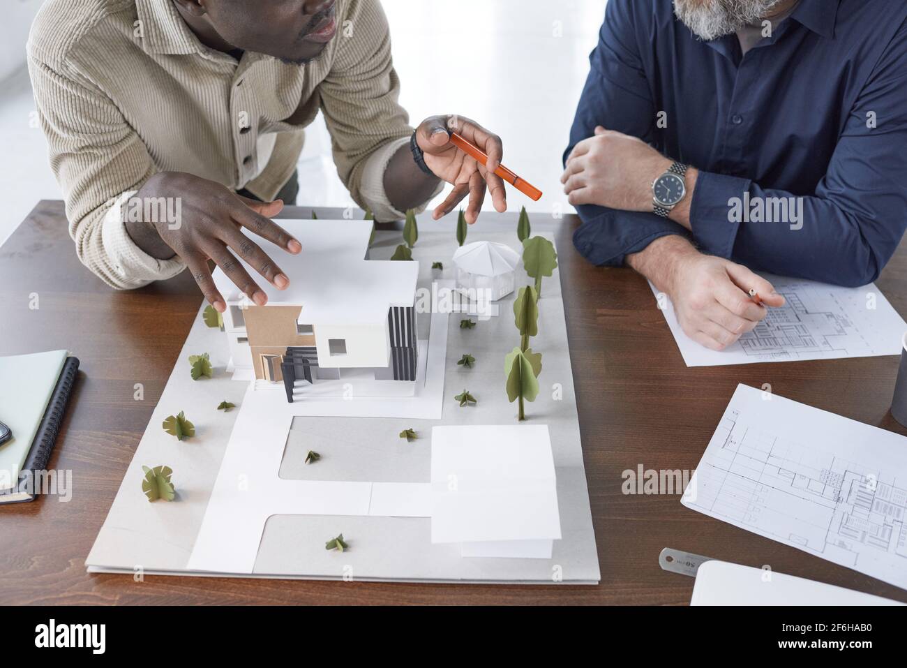 Primo piano del modello architettonico con costruzione di nuovo edificio e. architetti seduti al tavolo e discutere lo sviluppo del nuovo area Foto Stock
