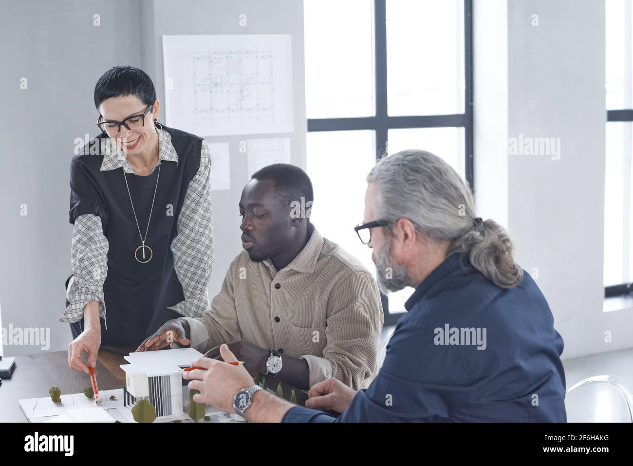 Gli uomini d'affari discutono del nuovo modello di costruzione durante la riunione di affari in ufficio Foto Stock