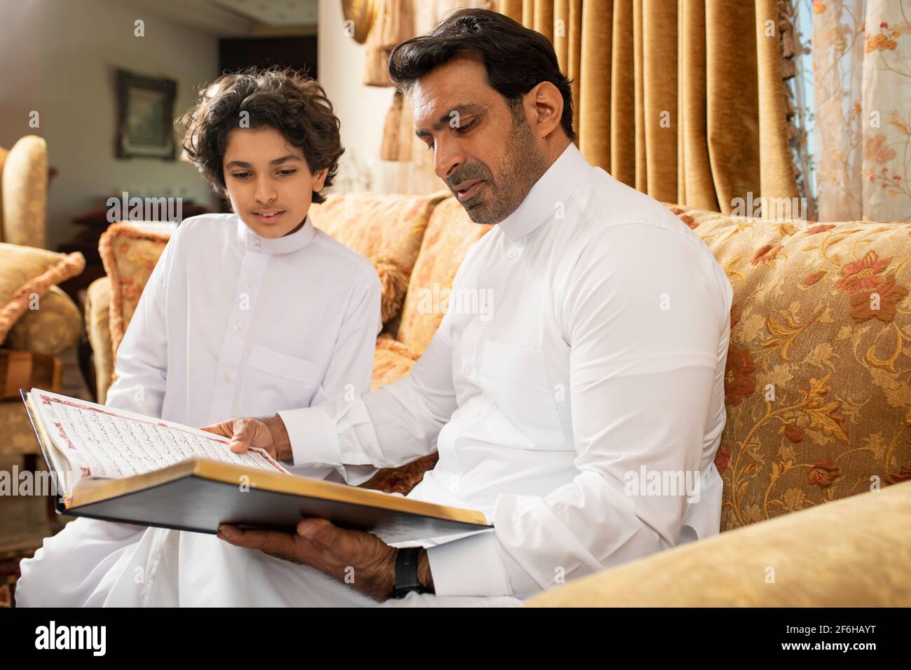 Padre arabo e Figlio che legge il Libro Sacro di Corano Foto Stock