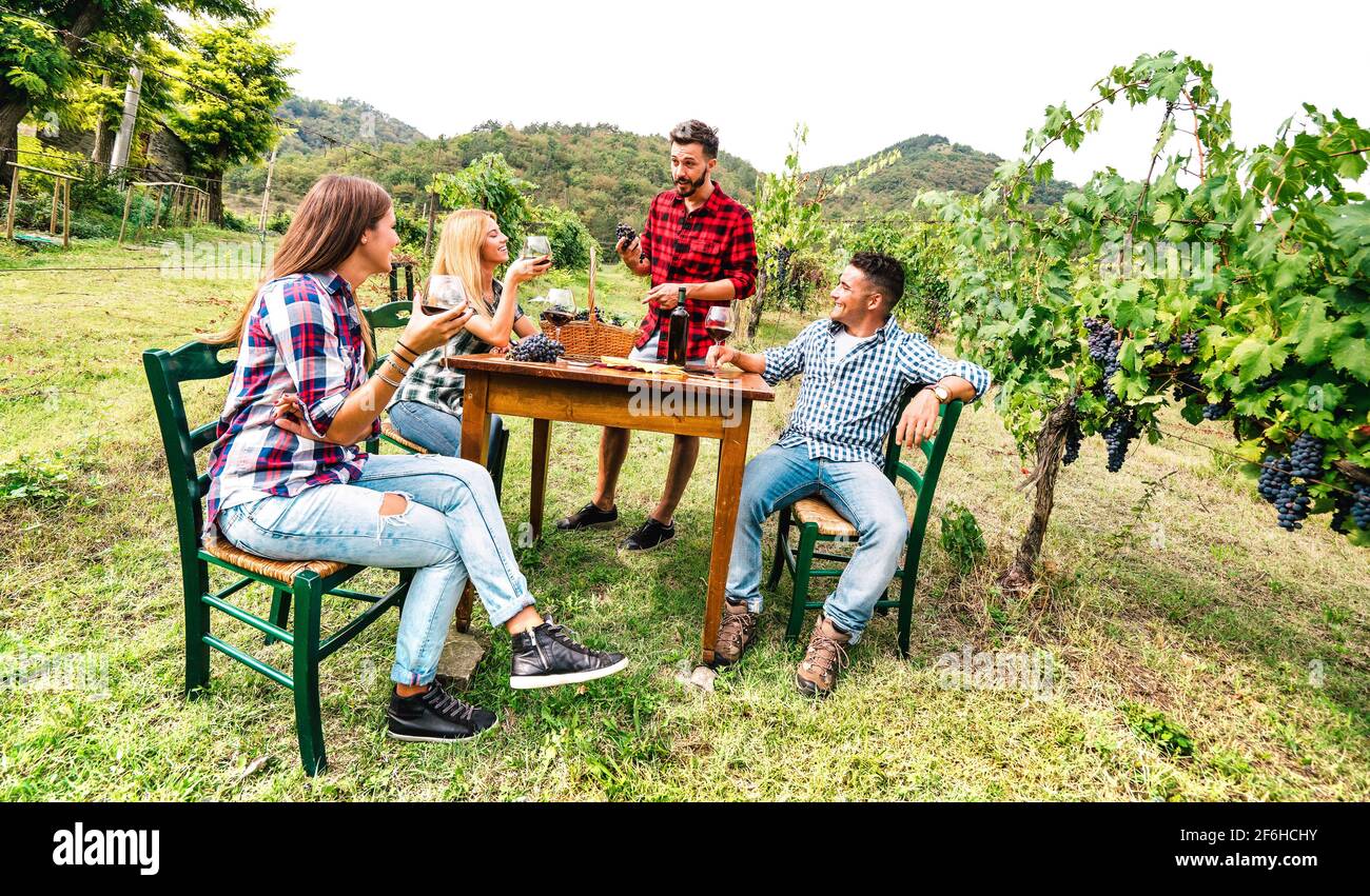 Felice gente che si diverte a bere vino rosso in vigna - Giovani amici che si divertono insieme nella fattoria di campagna casa Foto Stock