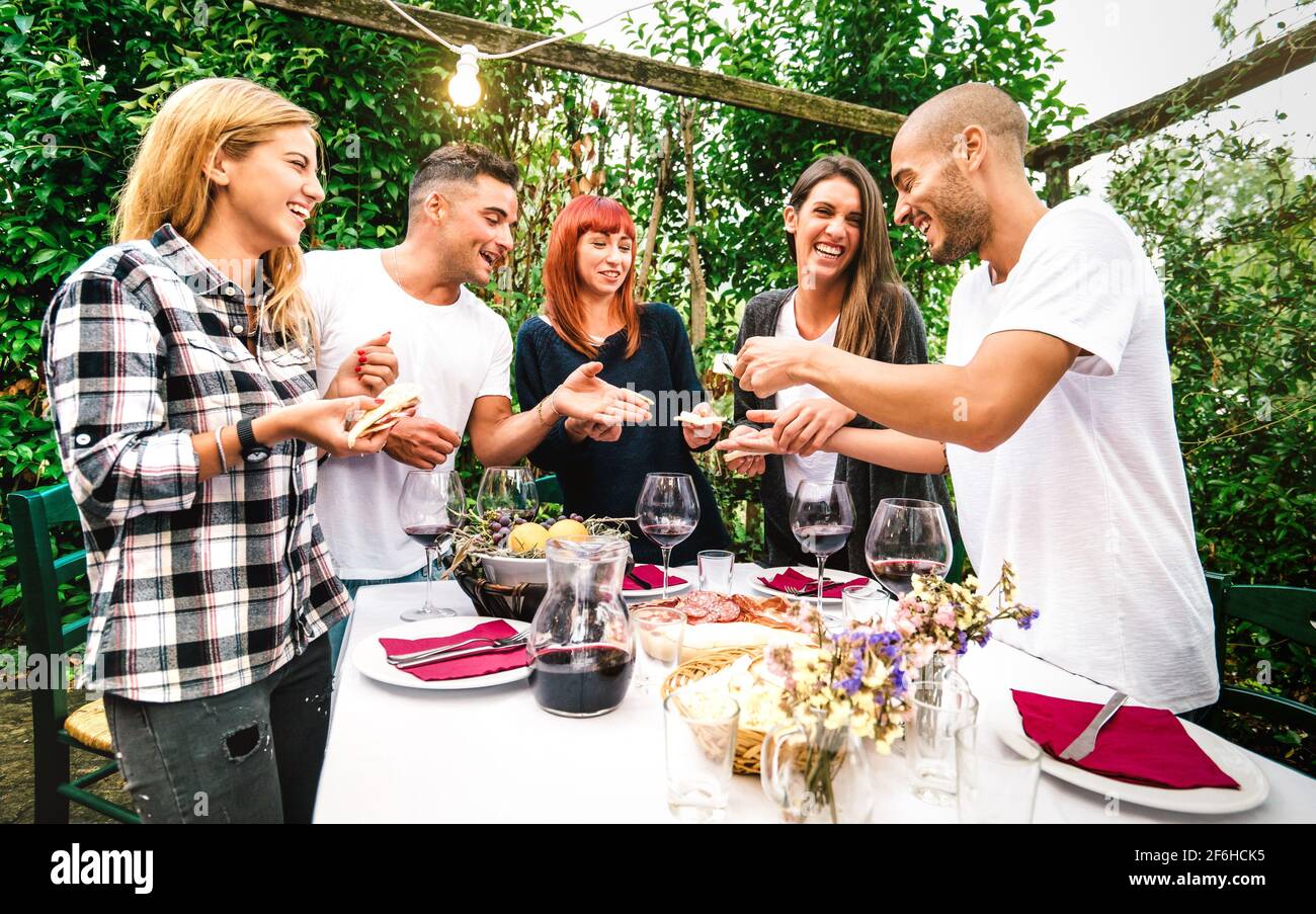 Giovani che si divertono a mangiare cibo locale e bere rosso Vino al festival del giardino di campagna - amicizia e vita stile di concetto con amici felici Foto Stock