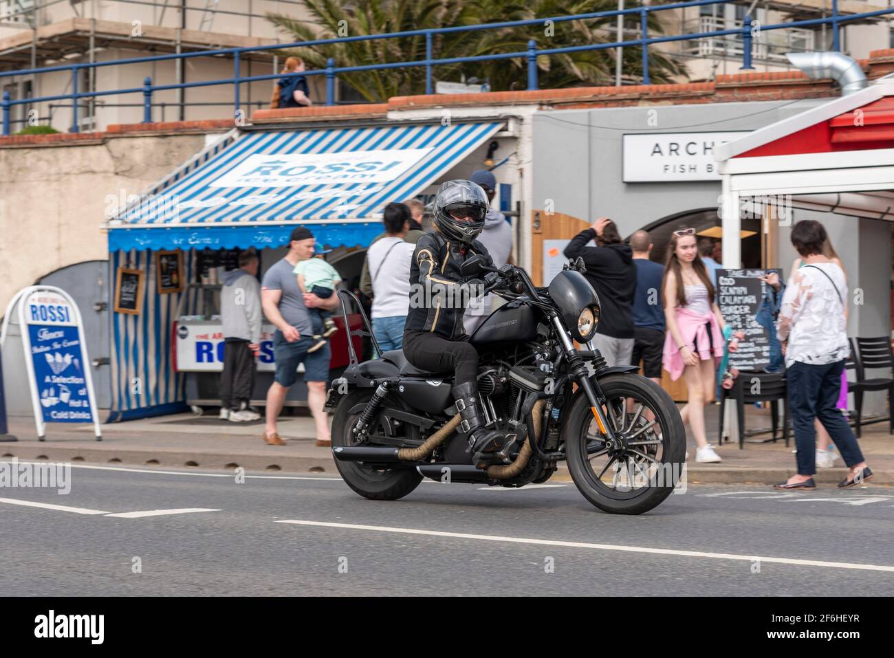 Una motocicletta Harley Davidson a Southend on Sea, Essex, Regno Unito. Passando per i ristoranti Arches sulla Western Esplanade. Abbigliamento nero Foto Stock