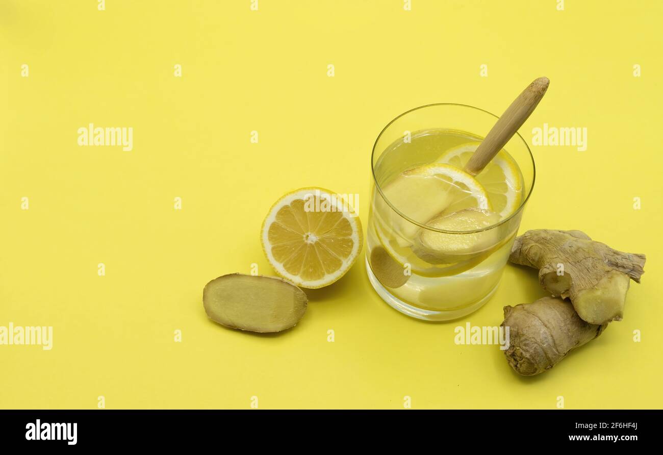 Inverno cura infusione di limone e zenzero fresco su sfondo giallo Foto Stock