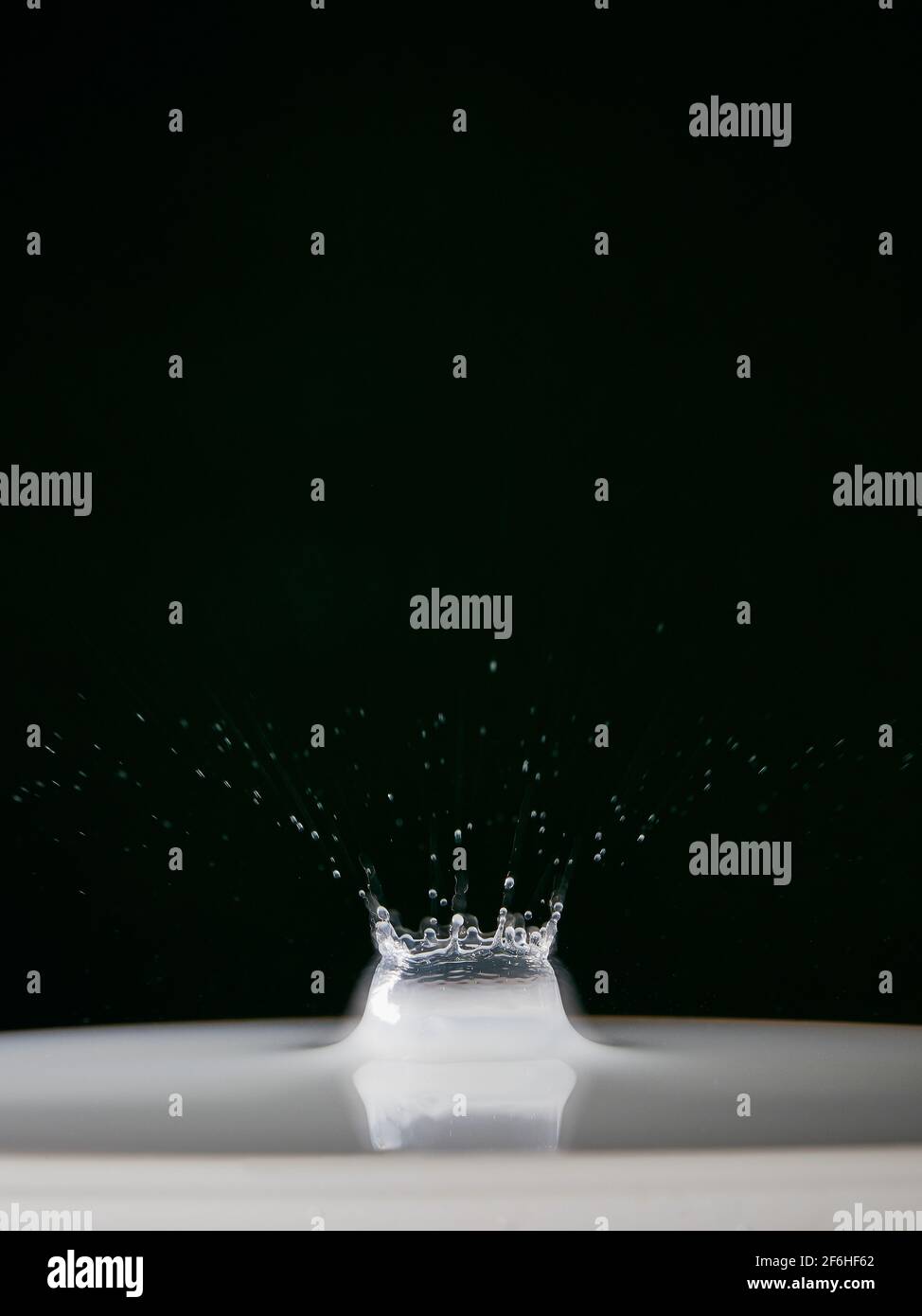 Una corona d'acqua è formata insieme a goccioline dopo a. una piccola quantità di acqua è stata fatta cadere da un'altezza su una superficie liscia delle acque Foto Stock