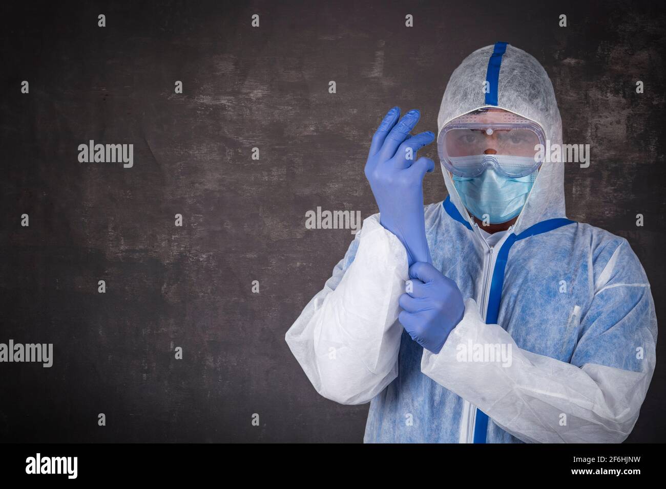 Uomo in tuta protettiva, maschera chirurgica e guanti in lattice con spazio per la copia del testo Foto Stock