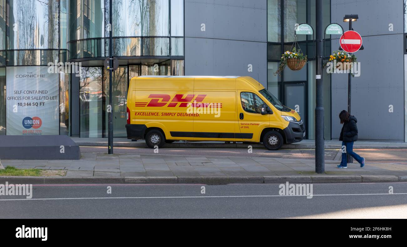 Un veicolo DHL per la consegna dei pacchi che effettua una consegna a un blocco di uffici. Foto Stock