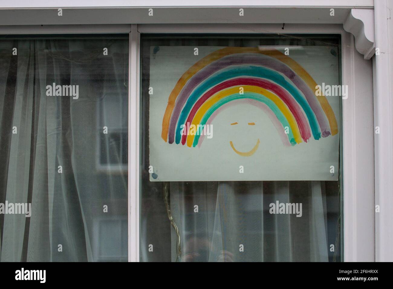 Un arcobaleno dipinto da un bambino è esposto in una finestra casa a sostegno del NHS durante la pandemia di Covid 19. Petersfield, Cambridge, Regno Unito. Foto Stock