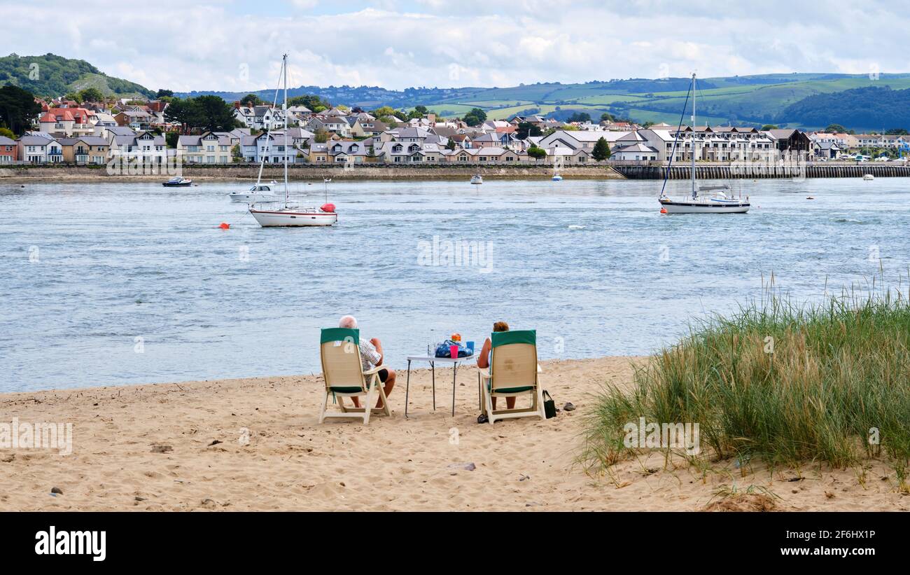 Una coppia trova il posto perfetto per godersi un picnic in spiaggia e guardare l'attività sul fiume Conway, Galles Foto Stock