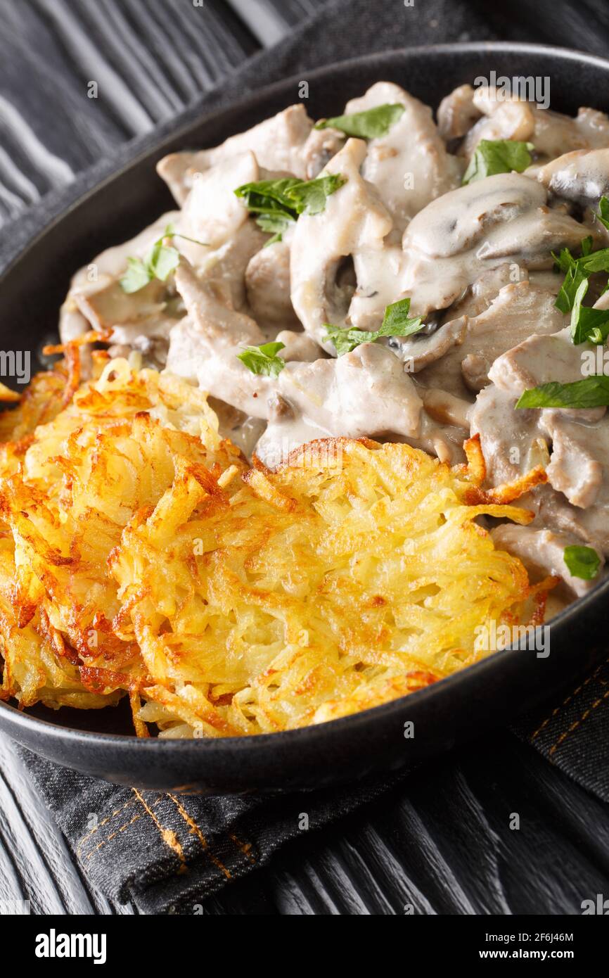 Zurcher Geschnetzeltes fatto di strisce di vitello a fette, vino bianco, funghi, panna e merletto servito con rosti in primo piano sul piatto. Ve Foto Stock