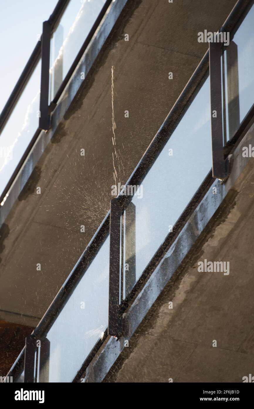 balconi esterni dell'edificio condominio con acqua che gocciola neve che si fonde dal tetto in calore di barriere in plexiglass sole con ringhiere in cemento Foto Stock
