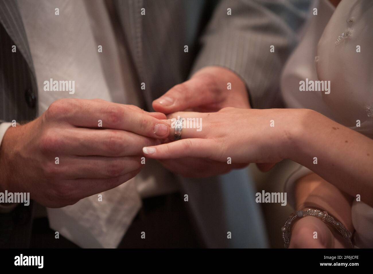 Primo piano di sposa che mette un anello di nozze sul dito dello sposo. Coppie che si scambiano gli anelli di nozze. Foto di alta qualità Foto Stock