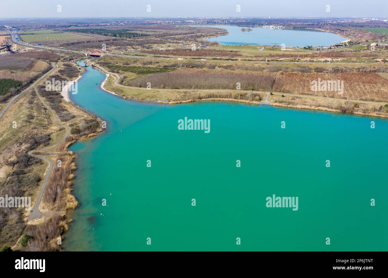 31 marzo 2021, Sassonia, Markkleeberg: Il canale tra il lago Markkleeberg (sul retro) e il lago Störmthal è chiuso da una parete di cumulo di fogli. Le incrinature nel canale tra i corpi idrici richiedono misure di sicurezza immediate. Il canale di Störmthal, lungo 850 metri, collega i due laghi - la serratura ora interessata dalle scivoloni nell'argine compensa la differenza di quattro metri nel livello dell'acqua dei corpi d'acqua. Secondo gli esperti, un crollo completo comporterebbe un'inondazione diffusa nelle aree urbane settentrionali, da Markkleeberg a Lipsia. Ora immersioni, surf, vela Foto Stock