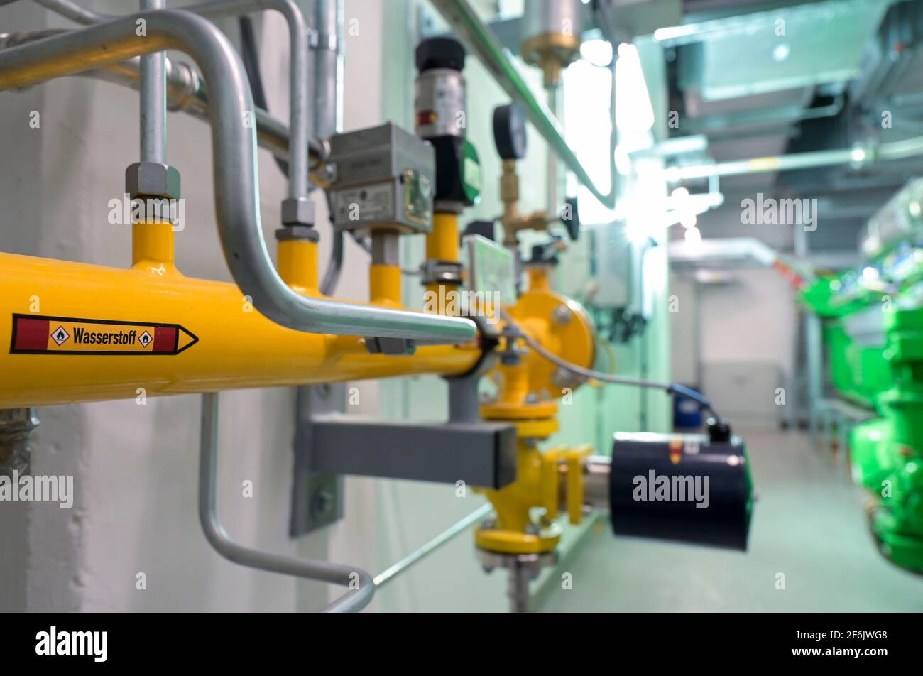 GERMANIA, Amburgo, un'unità di cogenerazione Megawatt per il riscaldamento e l'alimentazione con gas naturale o idrogeno verde, tubo H2 e generatore di motori a gas Jenbacher / DEUTSCHLAND, Amburgo, Hansewerk Natur, BHKW Blockheizkraftwerk 1 MW Klasse, das über Kraft-Wärme-Kopg suneine Siedlung mit Strom und Wärme versorgt, Energiequellen Erdgas oder Grüner Wasserstoff gewonnen aus erneuerbarer Energie, Wasserstoff Zuleitung fuer Jenbacher Gasmotor, der wahlweise grünen Wasserstoff oder Erdgas verbrennen kann Foto Stock