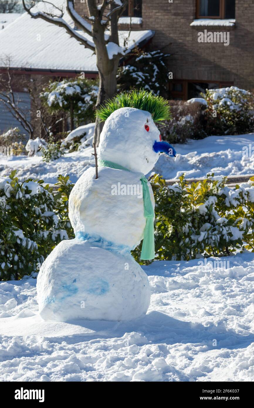 Un pupazzo di neve in un giardino con un mohawk Foto Stock
