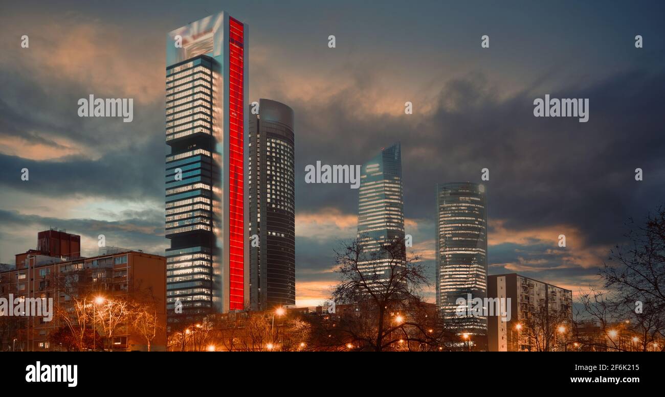 Su un cielo nuvoloso e cupo tramonto cielo sfondo illuminato con luci Cuatro Torres Four Towers Business Area notte vista città, quartiere situato in Paseo de l Foto Stock