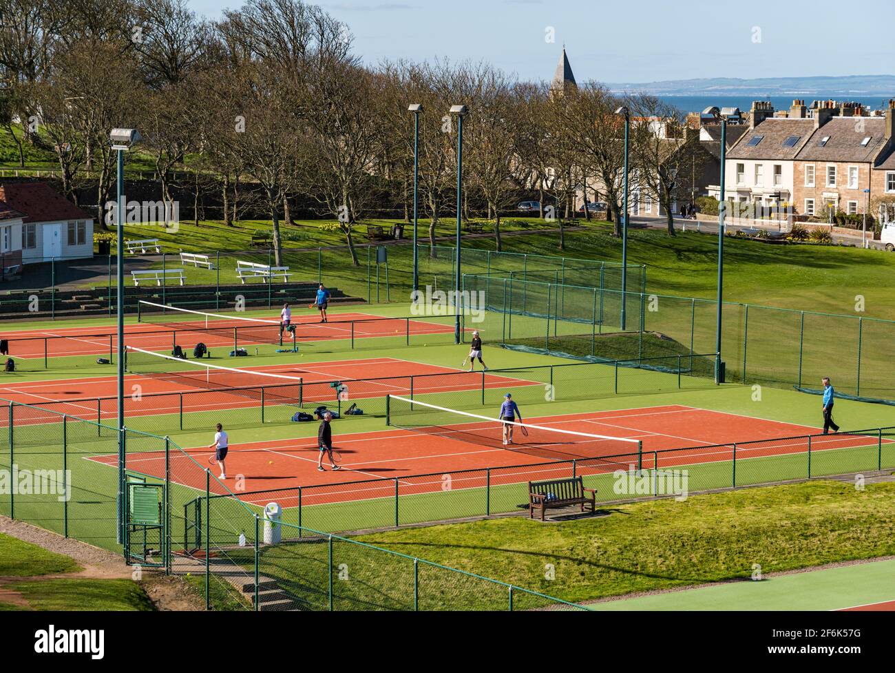 North Berwick, East Lothian, Scozia, Regno Unito, 1 aprile 2021. Regno Unito Meteo: Sole di primavera. Nella foto: I campi da tennis pubblici sono occupati da persone che si godono una partita di tennis il giorno prima di bloccare le restrizioni di facilità durante la pandemia Covid-19 Foto Stock