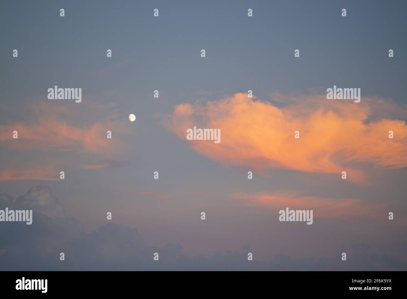 Cielo blu e nuvole arancioni. Cielo di tramonto con la luna, le nuvole sono colorate in arancione. Foto Stock